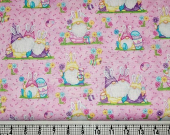 May include: Pink fabric with a repeating pattern of gnomes wearing bunny ears and holding Easter eggs. The gnomes are surrounded by flowers and scattered pastel dots.