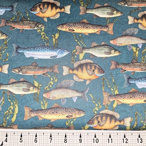 May include: A fabric with a repeating pattern of various fish species in shades of orange, brown, gray, and blue against a teal background with yellow seaweed illustrations. A ruler with inch measurements is at the bottom.