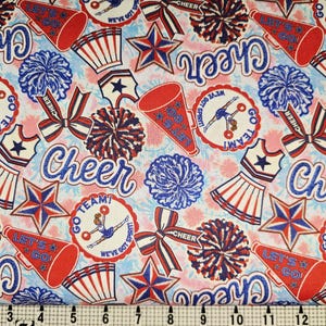 Puede incluir: Tela estampada con motivos de animadoras en rojo, blanco y azul. El diseño incluye megáfonos, estrellas, pompones, lazos y la palabra "Cheer". El fondo presenta un patrón floral en rosa claro y azul, ideal para manualidades.