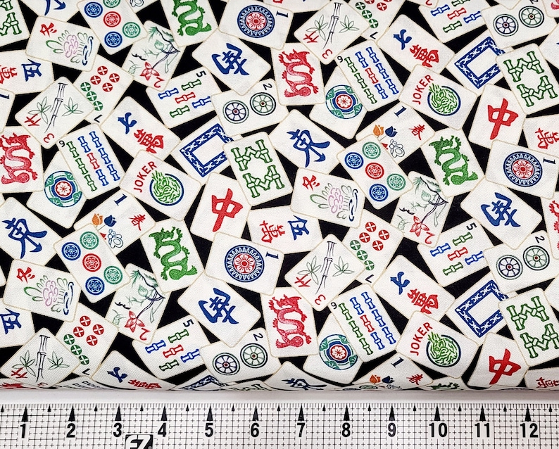 Op de afbeelding: Zwarte stof met een herhalend patroon van witte mahjong-tegels. De tegels bevatten Chinese karakters, cijfers en symbolen. De stof is perfect voor knutselprojecten.