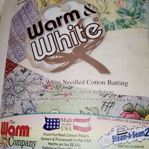 以下が含まれることがあります： Warm & Whiteのコットンバッティングの白いパッケージ。パッケージには、綿花のボールのグラフィックと「Wonderfully White Needled Cotton Batting」というテキストが記載されています。パッケージには、赤、白、青のアメリカ国旗のグラフィックと「Made in the USA」というテキストも記載されています。