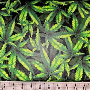 May include: A close-up of a fabric with a repeating pattern of green marijuana leaves on a black background.