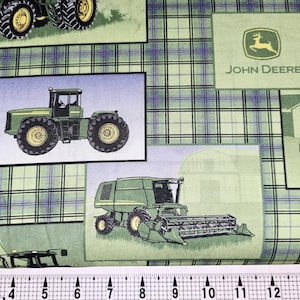 Könnte beinhalten: Grüner und schwarzer John Deere Traktor Stoff mit kariertem Hintergrund. Der Stoff zeigt mehrere Bilder von Traktoren, Mähdreschern und dem John Deere Logo.
