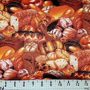 May include: A close-up of a fabric with a repeating pattern of various breads and pastries. The fabric is brown and orange with a variety of textures and shapes. The fabric is measured with a ruler in inches.
