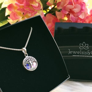 May include: A silver necklace with a tree of life pendant featuring a colourful abalone shell inlay. The necklace is displayed in a black velvet box with the brand name "JewelSis &" and the text "HANDCRAFTED 925 SILVER JEWELRY".
