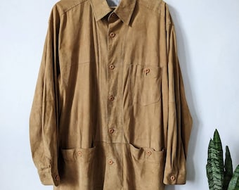 May include: A brown suede shirt with a button-up front and two large pockets on the bottom. The shirt has a label that reads "LEUTYLER" on the collar.