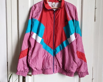 Może przedstawiać: Vintage kurtka wiatrówka w kolorze różowym, czerwonym, niebieskim i białym z zamkiem błyskawicznym i logo Puma po prawej stronie.
