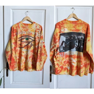May include: Orange and yellow tie-dye long-sleeve shirt with a black and white image of a band on the back. The band's name, "Moonspell", is printed on the front and back of the shirt.