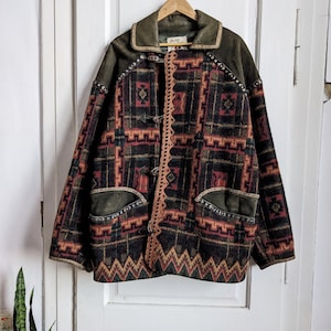 May include: A brown, green, red, and yellow patterned jacket with suede accents and leather toggles. The jacket has a collar and two pockets.