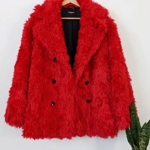 Puede incluir: Una chaqueta de piel sint&eacute;tica roja con cierre de doble botonadura y botones negros. La chaqueta est&aacute; colgada en una percha de madera.