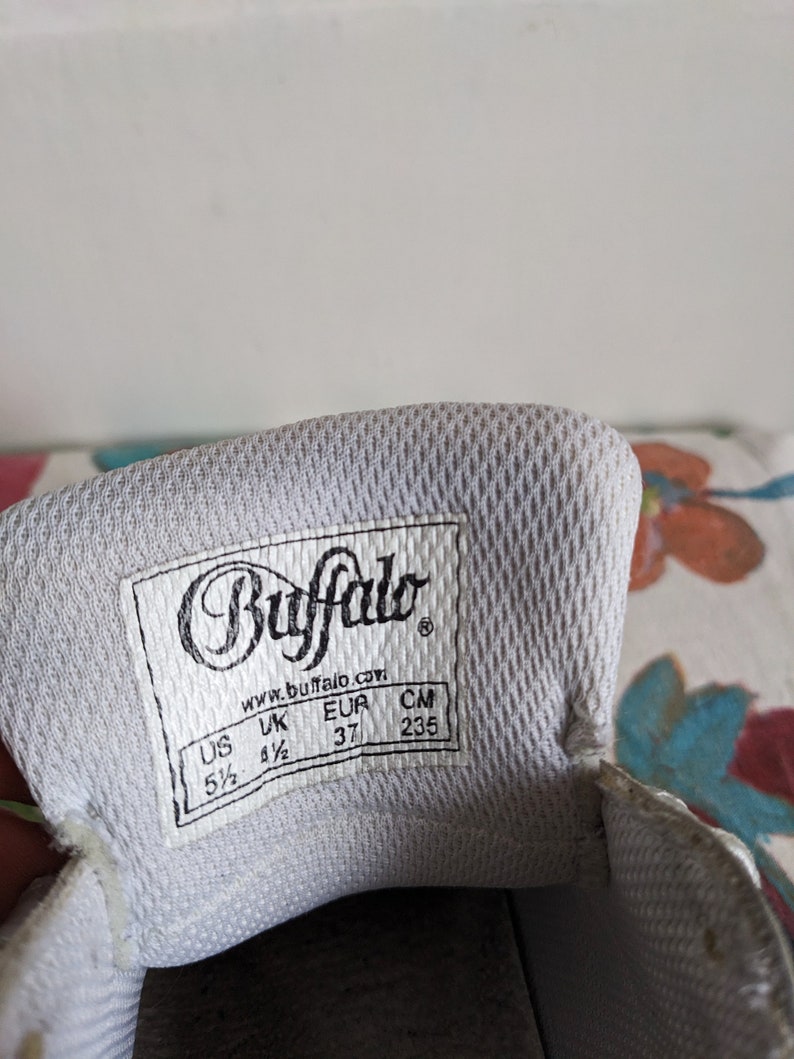 Op de afbeelding: Witte schoenzool met een zwart label waarop "Buffalo" en "www.buffalo.com" staat. Het label toont ook de schoenmaat in US, UK, EUR en CM: 5 1/2, 4 1/2, 37, 235.