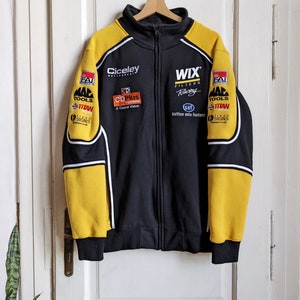 May include: Black and yellow zip-up jacket with sponsor logos. The jacket features white accents, a stand-up collar, and the logos of "Ciceley Motorsport", "WIX Filters Racing", and "CDPlus". The sleeves and shoulders are yellow.