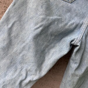 K&ouml;nnte beinhalten: Nahaufnahme einer hellblauen Jeans, die die Textur und Details des Stoffes hervorhebt. Das Bild zeigt den oberen Teil der Jeans, einschlie&szlig;lich einer Tasche und der N&auml;hte.