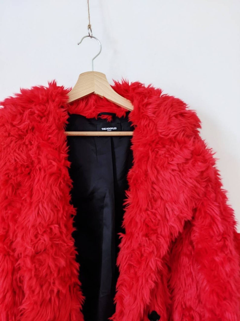 Puede incluir: Una chaqueta de piel sint&eacute;tica roja con forro negro y una etiqueta que dice "THE KOOPLES".