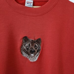May include: Red sweatshirt with an embroidered wolf head on the front. The sweatshirt has a Jerzees tag with the size L and the number 562.