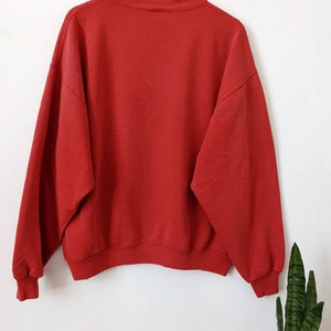 May include: A red crew neck sweatshirt with long sleeves.