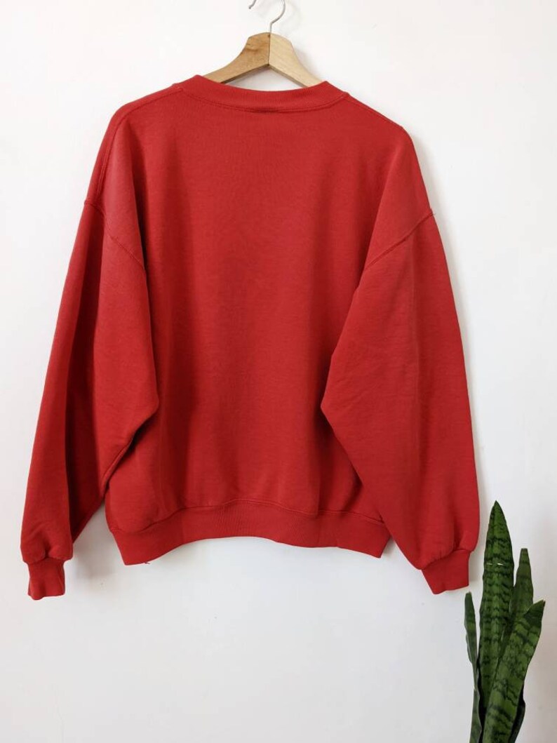 May include: A red crew neck sweatshirt with long sleeves.