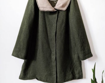 May include: A green wool coat with a large, cream-colored collar. The coat has a button closure and a simple design.