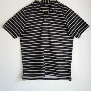 May include: Black and white striped polo shirt hanging on a wooden hanger. The short-sleeved shirt has a collared neckline and a three-button placket. The horizontal stripes are evenly spaced.
