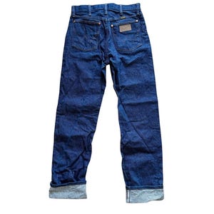 Op de afbeelding: Donkerblauwe denim jeans met een klassiek vijf-zakken ontwerp. De jeans hebben een bruine leren patch en zijn omgeslagen bij de enkels. De achterzakken hebben een kenmerkend stikselpatroon. Een tijdloze garderobe-musthave.