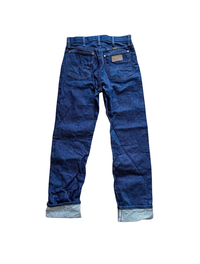 Op de afbeelding: Donkerblauwe denim jeans met een klassiek vijf-zakken ontwerp. De jeans hebben een bruine leren patch en zijn omgeslagen bij de enkels. De achterzakken hebben een kenmerkend stikselpatroon. Een tijdloze garderobe-musthave.