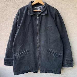 Puede incluir: Chaqueta vaquera gris oscuro con cremallera completa, dos bolsillos delanteros y un peque&ntilde;o parche con el logotipo. La chaqueta tiene cuello y un emblema redondo en el pecho. La etiqueta dice "VERSACE CLASSIC V2".