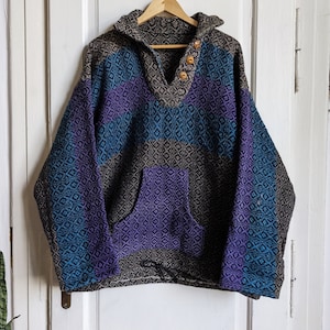 May include: A brown, blue, and purple patterned sweater with a hood and a single button closure. The sweater has a kangaroo pocket.