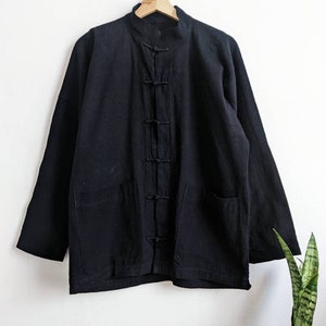 May include: A black cotton jacket with a mandarin collar and a button closure. The jacket has two pockets on the front and long sleeves.