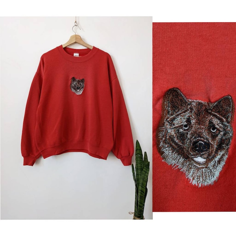 May include: Red sweatshirt with an embroidered wolf face on the front.