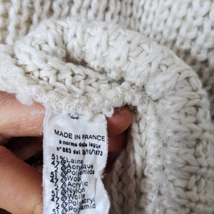 May include: A white knitted sweater label with the text "MADE IN FRANCE" and a list of materials and percentages, including "51% Laine", "47% Acrylique", "2% Polyamide", "47% Wool", "2% Acrylic", "51% Nylon", "47% Polyacryl", "2% Polamid", "47% Acry!", "51% Polyamide", "47% Lana", "Acrilic", "Poliamm".