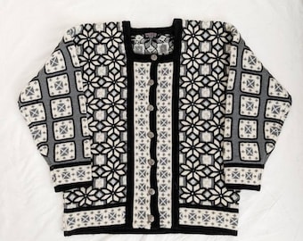 May include: A black and white patterned cardigan with a button-up front. The cardigan has a geometric design with a black background and white and gray accents.
