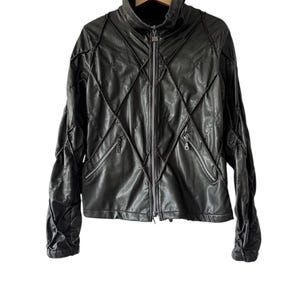 May include: Black leather jacket with a high collar and a diamond-stitched design. The jacket features a zip closure and two front pockets. The sleeves are textured, and it hangs on a wooden hanger.