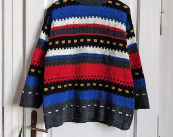 May include: A colorful striped sweater with a high neck. The sweater is made of a soft, knitted fabric and features a variety of colors, including red, blue, black, white, and gold.