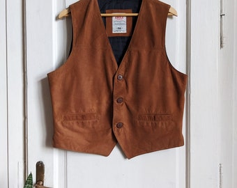 May include: A brown leather vest with a button closure and two pockets. The vest has a black lining and a label that reads "Eagle" in red.