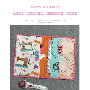 May include: A pink and orange sewing case with a zipper closure and multiple pockets. The case is open and filled with sewing supplies, including scissors, thread, and a rotary cutter. The case is decorated with a sewing machine pattern and the text "CRAFTY LIL MOUSE" and "MAXI TRAVEL SEWING CASE".