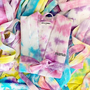 May include: A pink, blue, and yellow tie-dye waffle robe with a white label that says "BFFs & BABES" and a purple embroidered word "mama".
