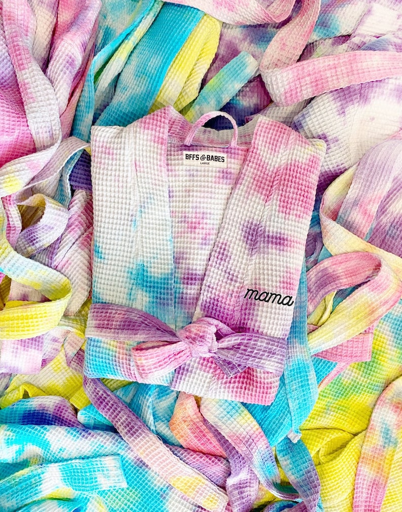 May include: A pink, blue, and yellow tie-dye waffle robe with a white label that says "BFFs & BABES" and a purple embroidered word "mama".