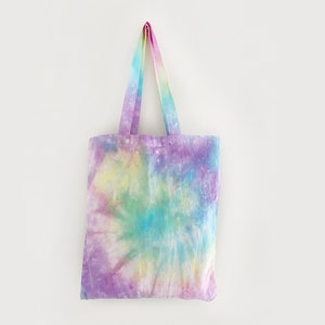 May include: A tie-dye tote bag with a swirl pattern in shades of purple, blue, green, yellow, and pink.