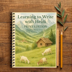 以下が含まれることがあります： 「Learning to Write with Heidi」というタイトルの、小屋、ヤギ、山々の風景イラストが描かれたスパイラル綴じノート。2本の鉛筆と、木の表面にあるノートの隣には緑の小枝があります。