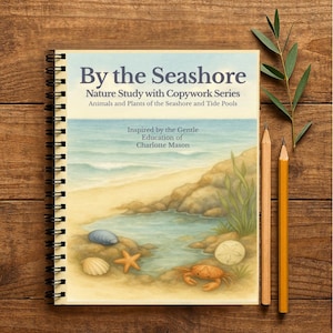 Puede incluir: Un cuaderno con espiral titulado "By the Seashore" con una ilustración de una escena de playa. La portada presenta una pintura de acuarela de una costa con un cangrejo, una estrella de mar y conchas. Dos lápices y una ramita de vegetación se colocan junto al cuaderno sobre una superficie de madera.