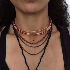 Könnte beinhalten: Eine mehrlagige Halskette mit einem Kupfer-Choker, Kettengliedern und einem Anhänger mit einem umwickelten Kristall.