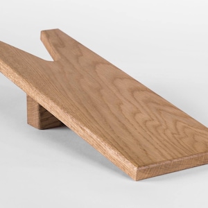May include: A wooden boot jack with a natural finish. The jack is made of solid wood and has a V-shaped opening for inserting boots.