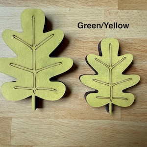 May include: Two flat, leaf-shaped cutouts in a light green-yellow color, featuring dark brown edges and engraved vein details. The larger leaf is on the left and the smaller leaf is on the right. The text "Green/Yellow" is printed above the smaller leaf.