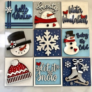 May include: Nine wooden signs with winter themes. The signs feature a snowman, snowflake, ice skates, a robin, and the phrases "hello winter", "frosty", "winter wonderland", "baby it's cold", "let it snow".