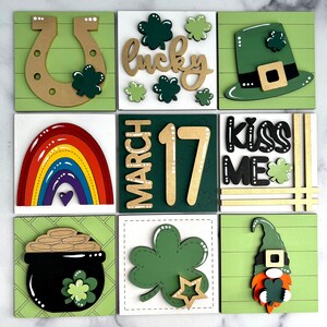 May include: Nine wooden squares with a St. Patrick's Day theme. The squares feature a rainbow, a pot of gold, a shamrock, a leprechaun, a horseshoe, a hat, the words "lucky" and "kiss me", and the date "March 17".