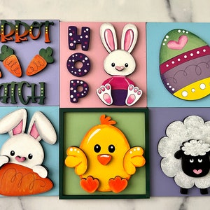 May include: Six wooden squares with a spring theme. Each square features a different design: a carrot patch, the word "HOP", a bunny holding a carrot, a chick, an Easter egg, and a sheep. The squares are painted in various colors, including purple, pink, blue, green, and yellow.