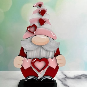 Nain debout sur l'étagère de la Saint-Valentin, joli nain avec 3 coeurs, chapeau à rayures, peint à la main ou inachevé pour le bricolage