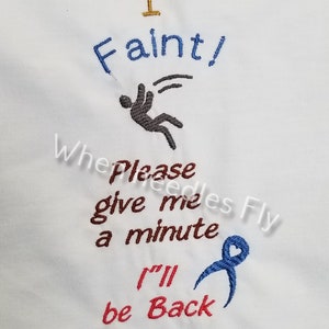May include: Embroidered design on a white fabric background. The design says "I Faint!" with a stick figure falling down. Below the figure, it says "Please give me a minute I'll be back" with a blue ribbon.