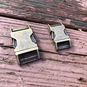 May include: Two antique gold-toned metal slider buckles. The buckles are rectangular with a smooth, slightly textured surface.