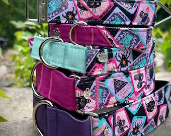 May include: A stack of five colorful dog collars with a black and white tarot card print. The collars are made of fabric and have silver metal hardware. The collars are stacked in order of color from top to bottom: black, pink, mint green, pink, and purple.